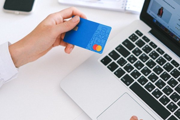 semplificare le spese e i propri conti bancari per ridurre le spese. nella foto una donna mentre fa shopping online con un pc e la carta di credito 